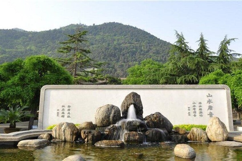 A rock garden with a waterfall, surrounded by trees and a mountain in the background. 4