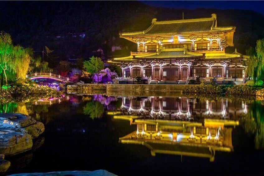 A traditional Chinese building with golden lighting, a reflection in the water, and a bridge in the foreground. 5