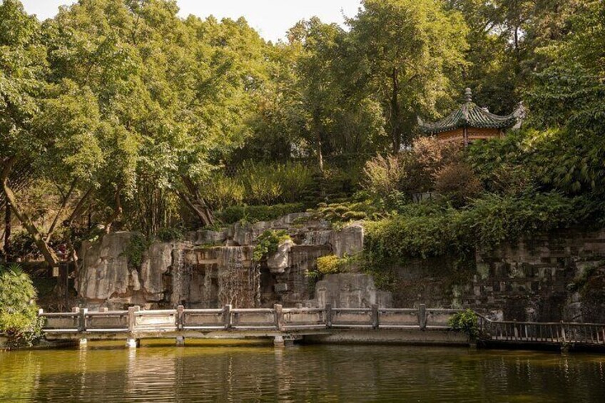 En traditionel kinesisk have med en bro over vand, frodig vegetation og et pagode. 2