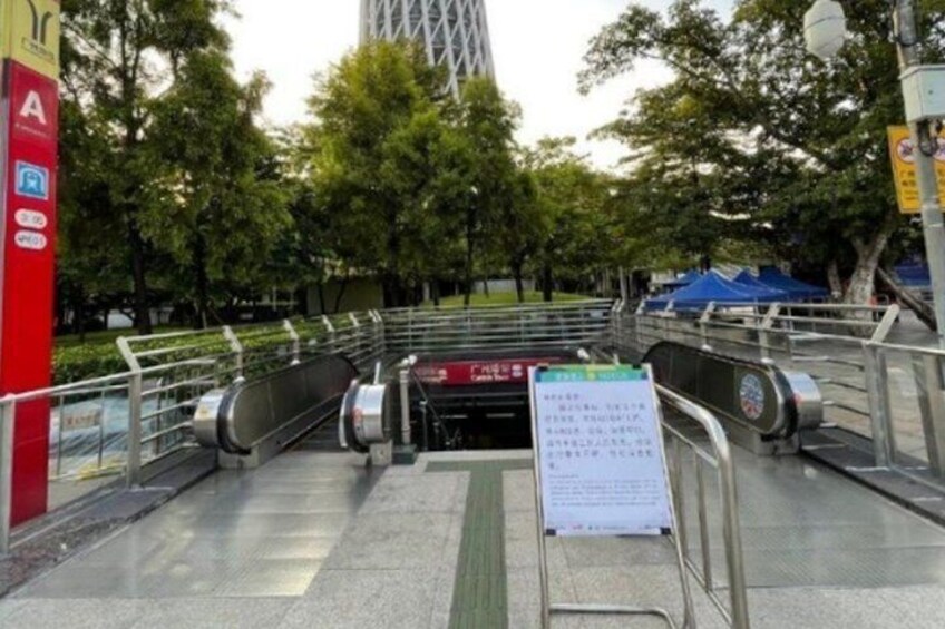 Una escalera mecánica al aire libre que lleva a un edificio, rodeado de árboles y un letrero rojo. 3