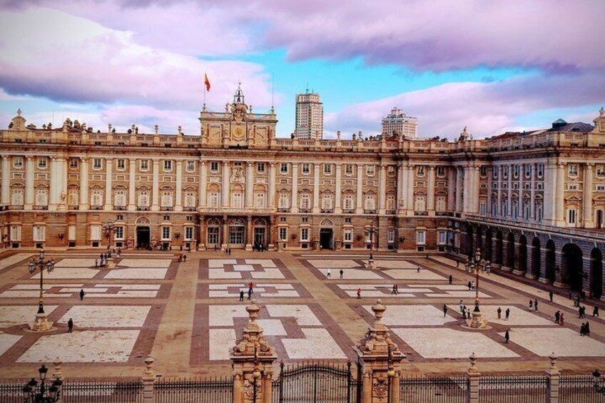 A large historic building with a symmetrical facade, a central courtyard, and a flag on top. 5