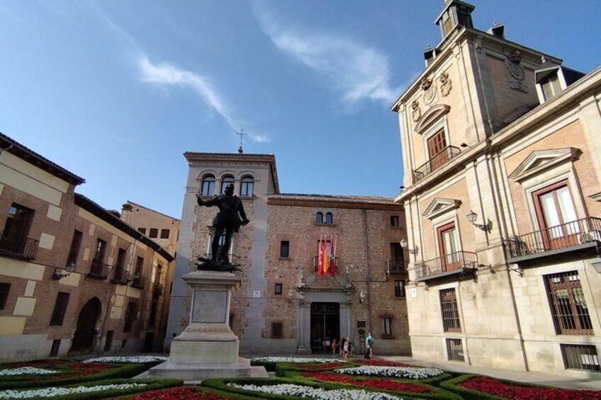 A historic building with a statue in front, surrounded by well-maintained flower beds. 3