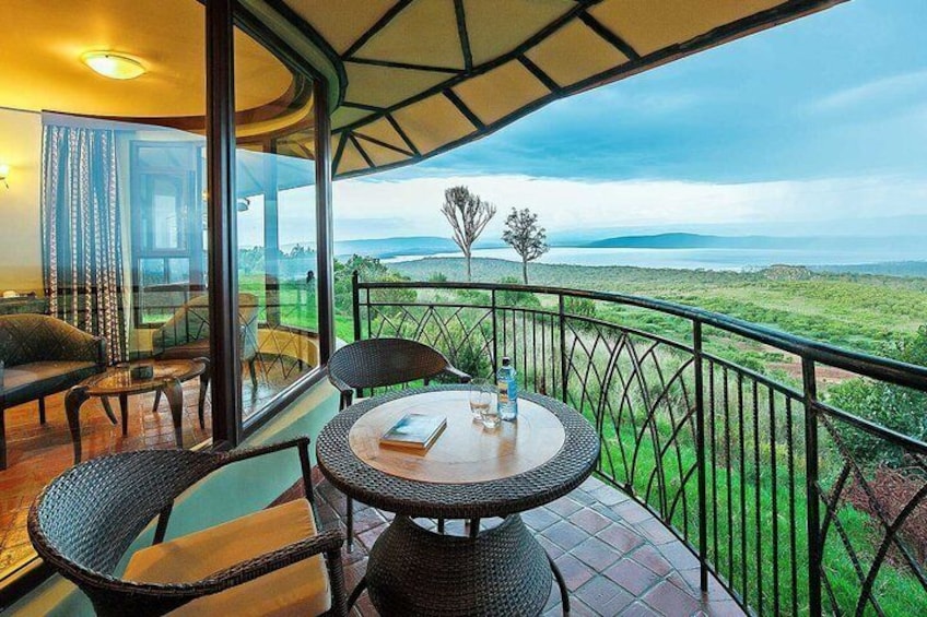 A balcony with wicker furniture, a table, and a view of a green landscape. 1