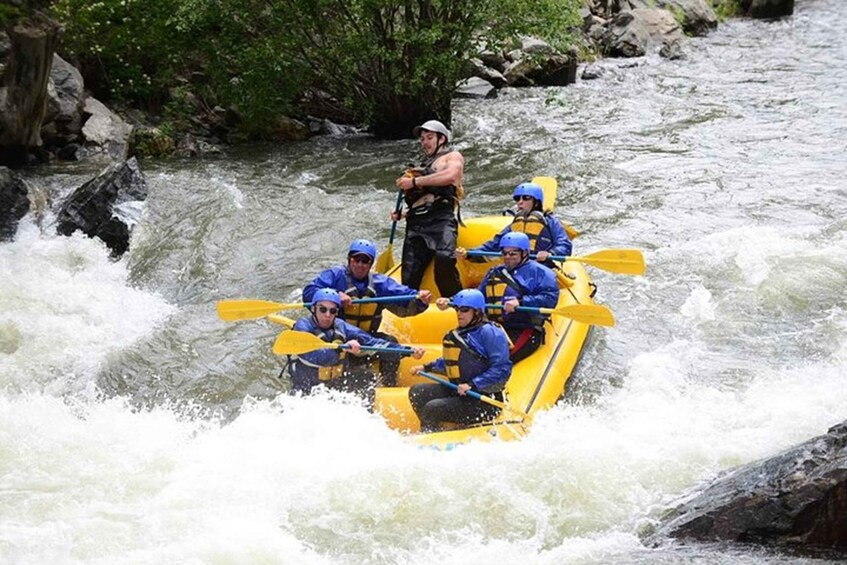 A group of people in a yellow raft navigating a river with rapids. 3