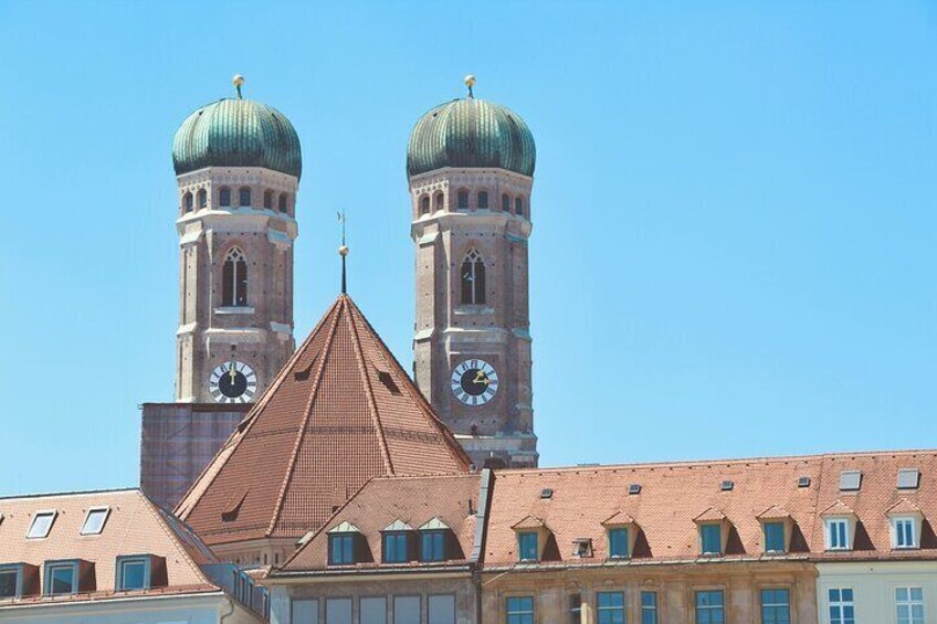 A building with two towers, each with a clock and a green dome. 2