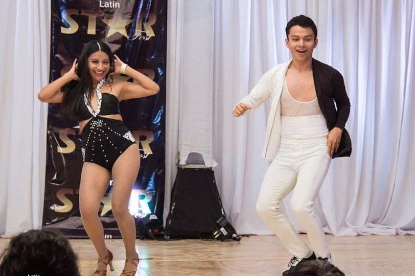 Two people dancing on a stage with a backdrop that includes the word 'Latin.' 3