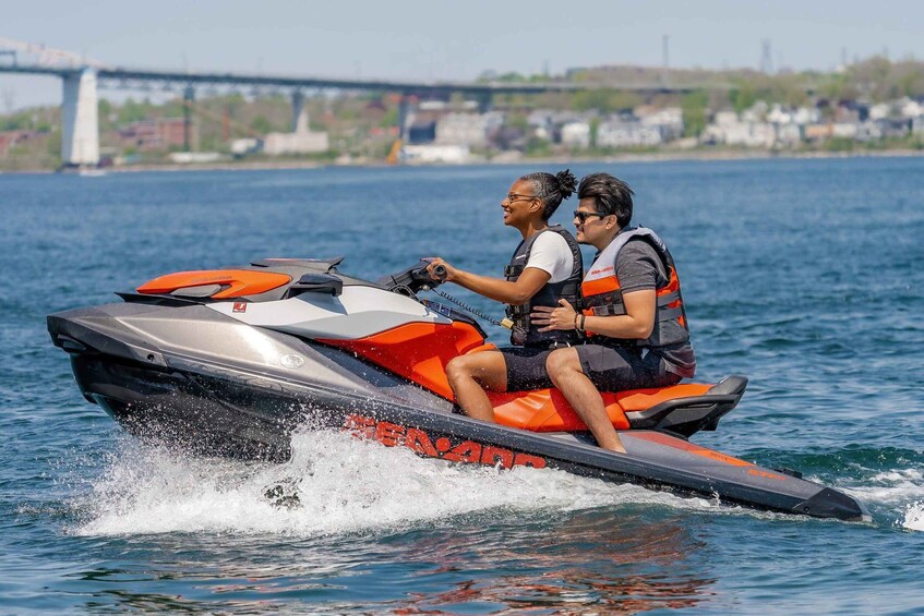 Two people on a jet ski with a bridge in the background. 4