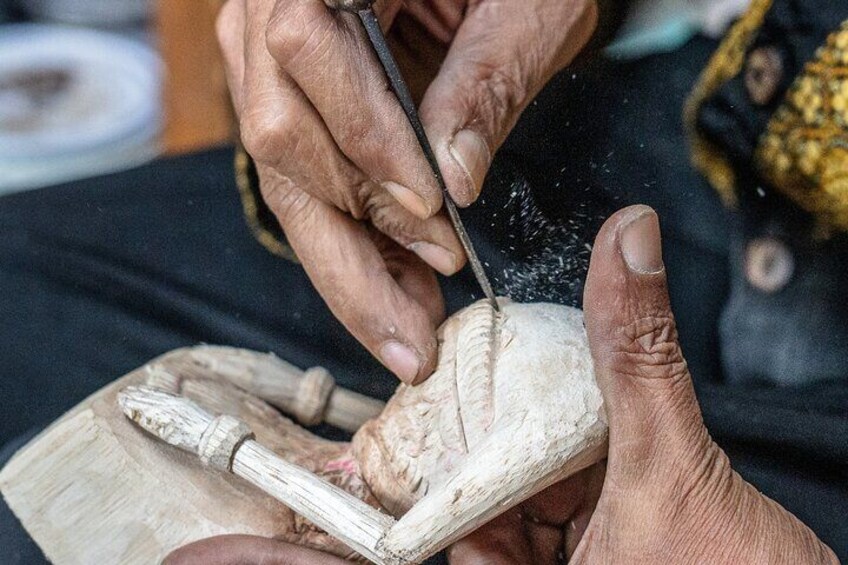 A person carving a wooden sculpture. 3