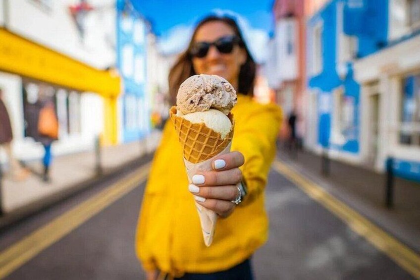 Eine Person hält einen Eisbecher in einer Straße. 5