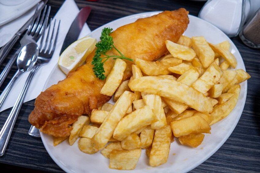 Ein Teller Fish and Chips mit einem Zitronenschnitz und Petersilie. 3