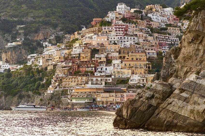 A coastal town with colorful buildings built on a hillside, overlooking a beach. 3