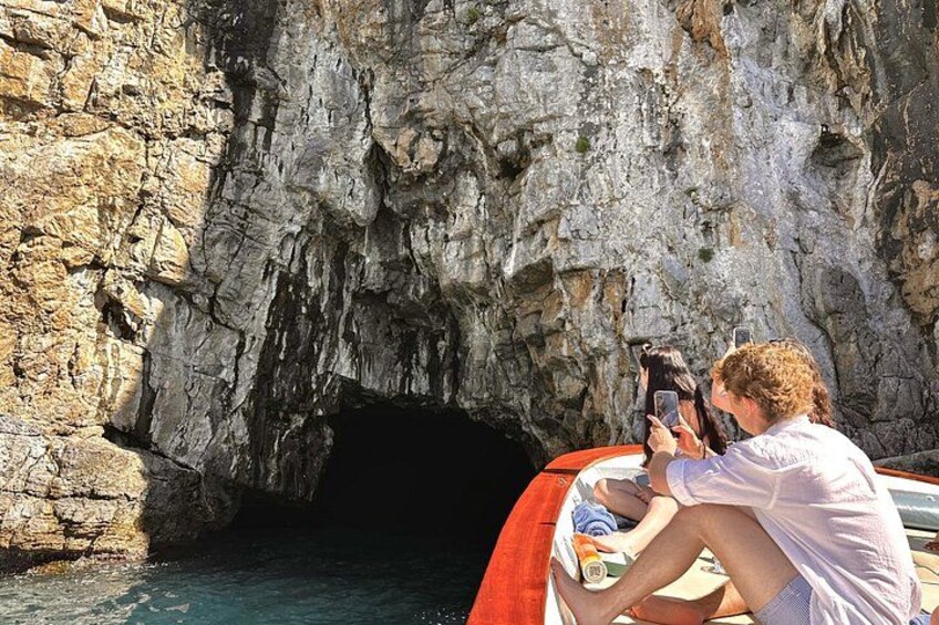 A person taking a photo of a rocky cave entrance with a boat nearby. 2