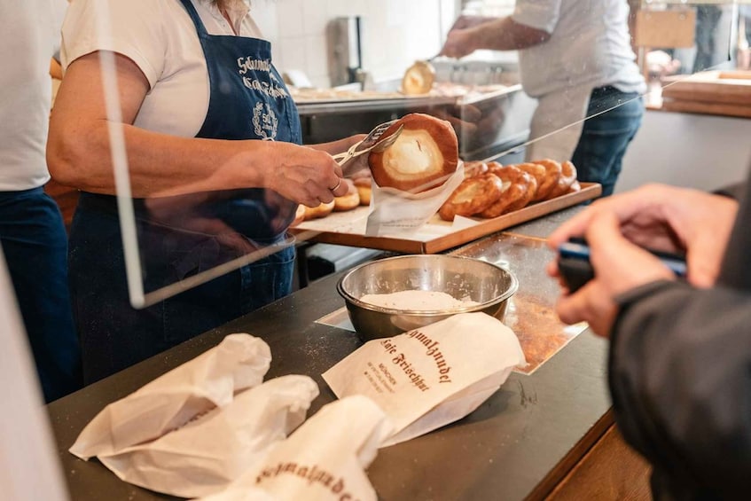 A person preparing food, possibly dough, with a bowl and a tray of bread. 2