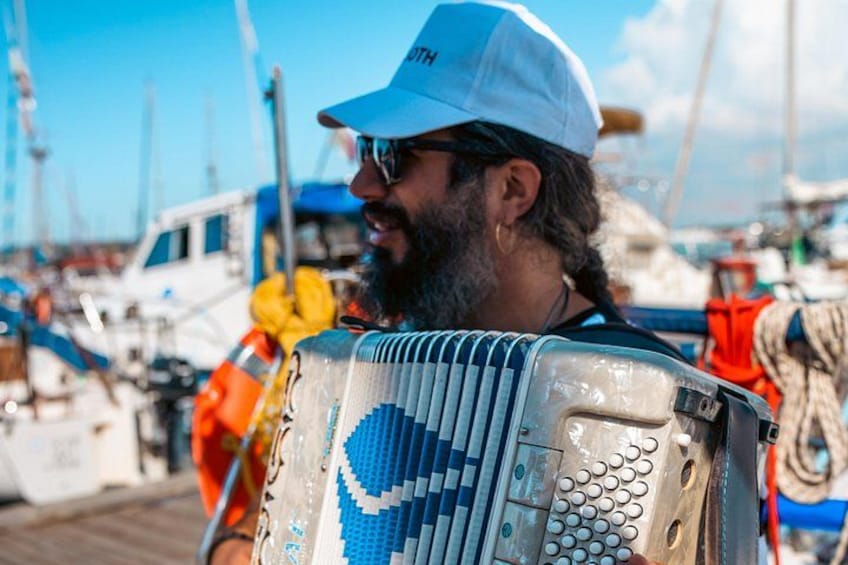 Una persona con un berretto bianco con un logo, in un porto turistico con barche sullo sfondo. 3