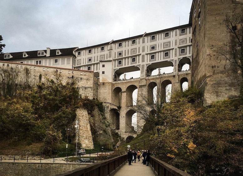 A stone bridge with arches, a pathway, and a building with multiple windows. 5