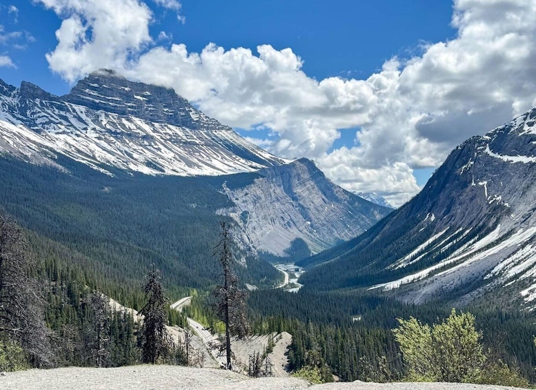 A mountain landscape with a clear sky, a valley, and a winding road. 3