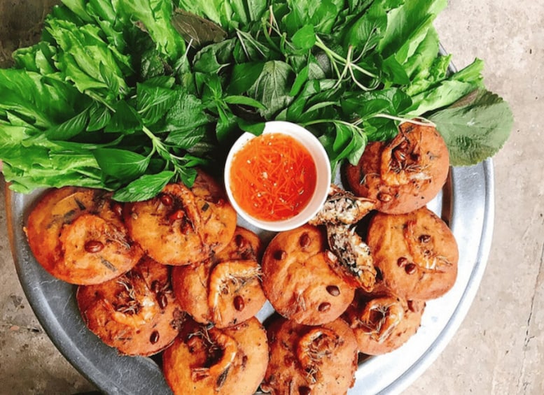 A plate of grilled shrimp with a side of fresh herbs and a bowl of red sauce. 4