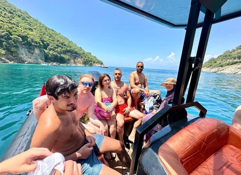 A group of people on a boat with a mountainous coastline in the background. 1