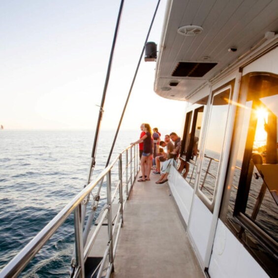 A group of people on a boat deck during sunset. 2
