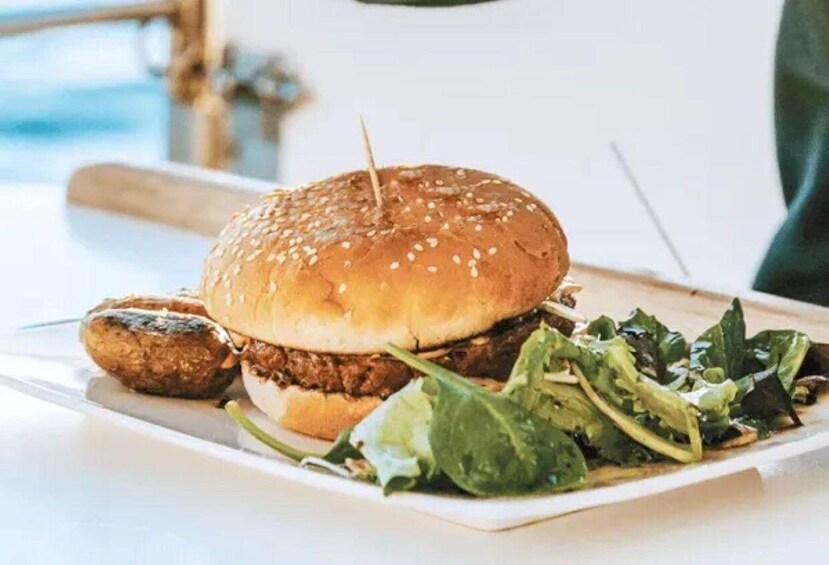 A chicken burger with sesame seed bun, a side of fries, and a leafy green salad on a white plate. 4