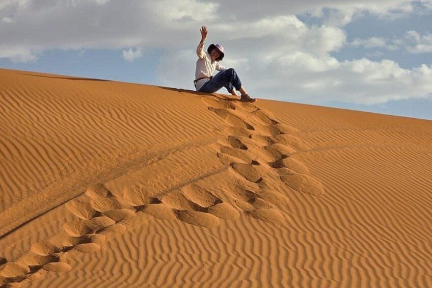 En person sidder på en sanddune med en klar himmel i baggrunden. 4