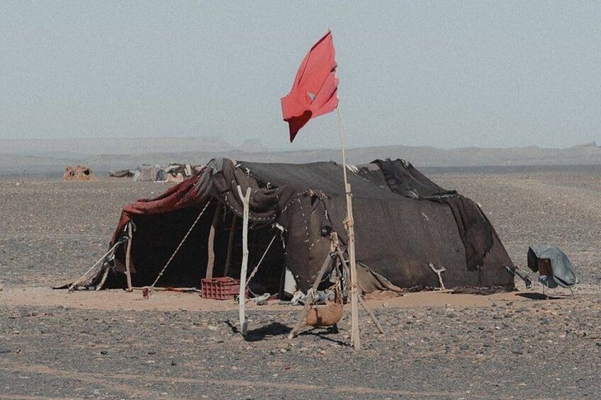Et telt med et rødt flag, et improviseret ly og et klippefyldt ørkenlandskab. 5