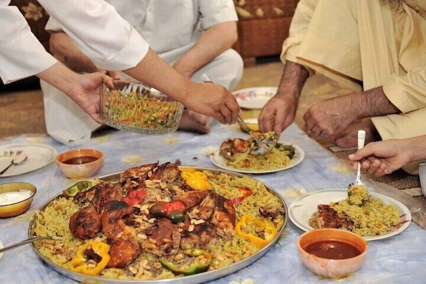 A large family meal with a variety of dishes, including a big platter of rice and meat, and several bowls of sauce. 3