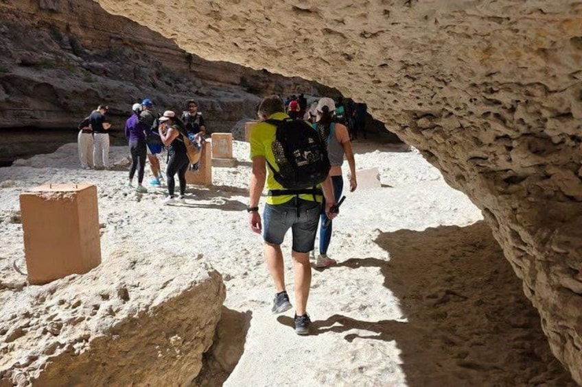 A group of people hiking in a rocky canyon with sandstone formations. 4