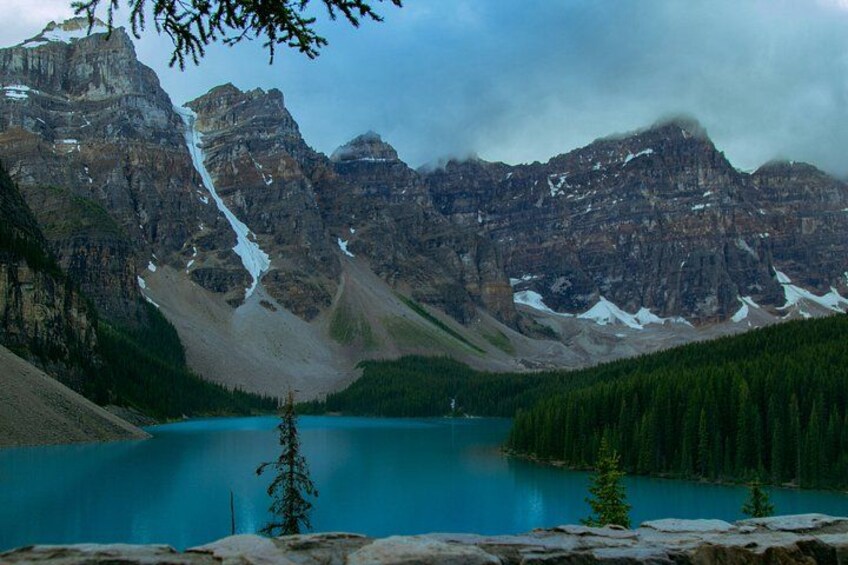 A mountain range with a turquoise lake, snow-capped peaks, and dense forest. 2