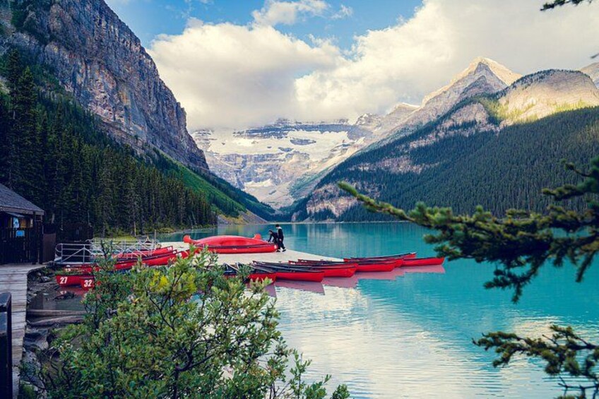 Un lago tranquilo con barcos rojos amarrados en la orilla, rodeado de montañas y árboles. 5
