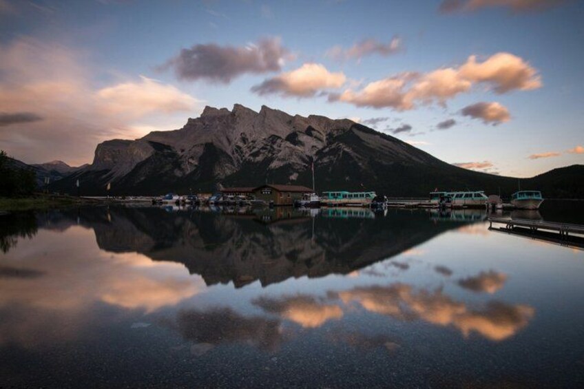 Una cordillera reflejada en un lago tranquilo con barcos y edificios a lo largo de la orilla. 3