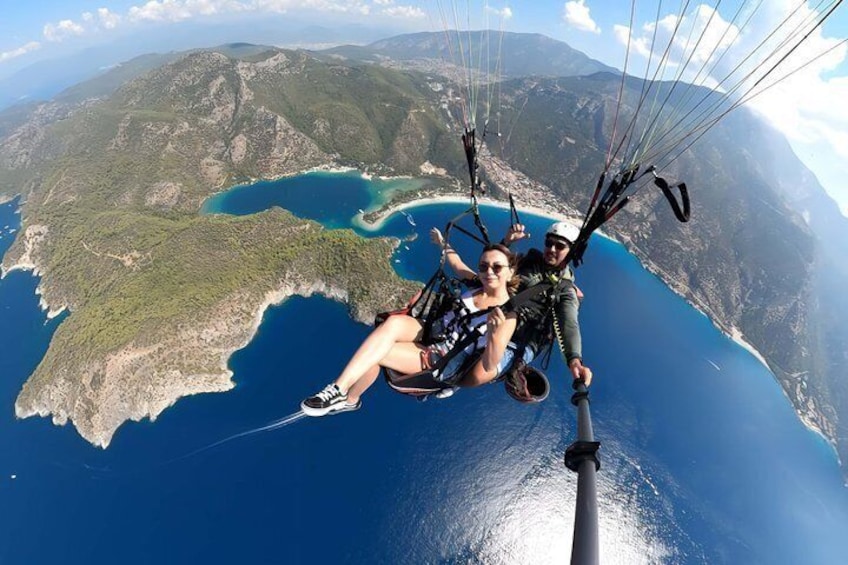 Une personne pratiquant le parapente au-dessus d’un paysage côtier, avec des montagnes et une étendue d’eau. 4