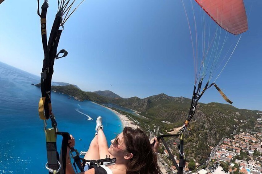 Une personne pratiquant le parapente au-dessus d’un paysage côtier, sous un ciel dégagé. 3