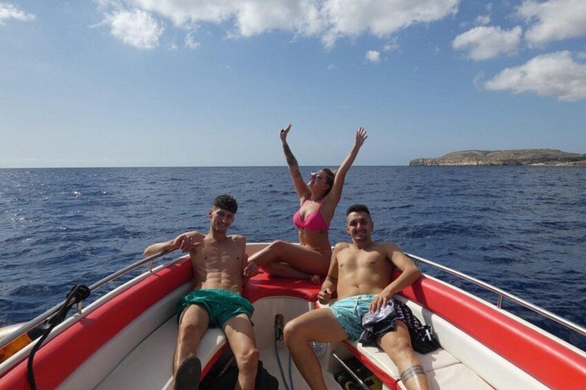 Three people on a red boat in the ocean with a clear sky and a distant landmass. 4
