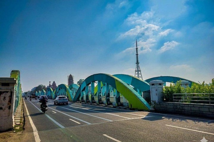 A bridge with green arches, a clear sky, and a tower in the distance. 2