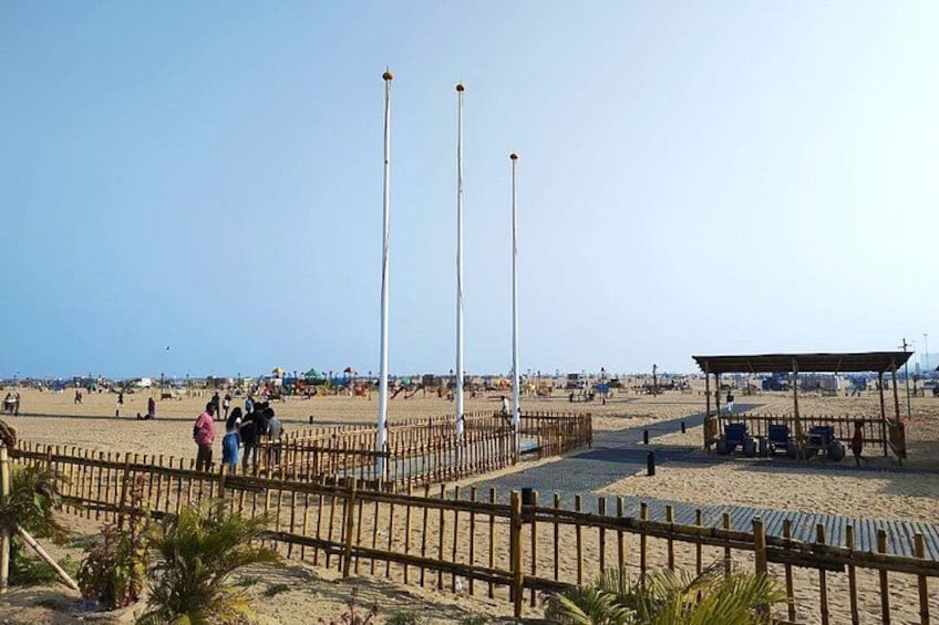 A beach with a fenced area, a pavilion, and tall poles. 3