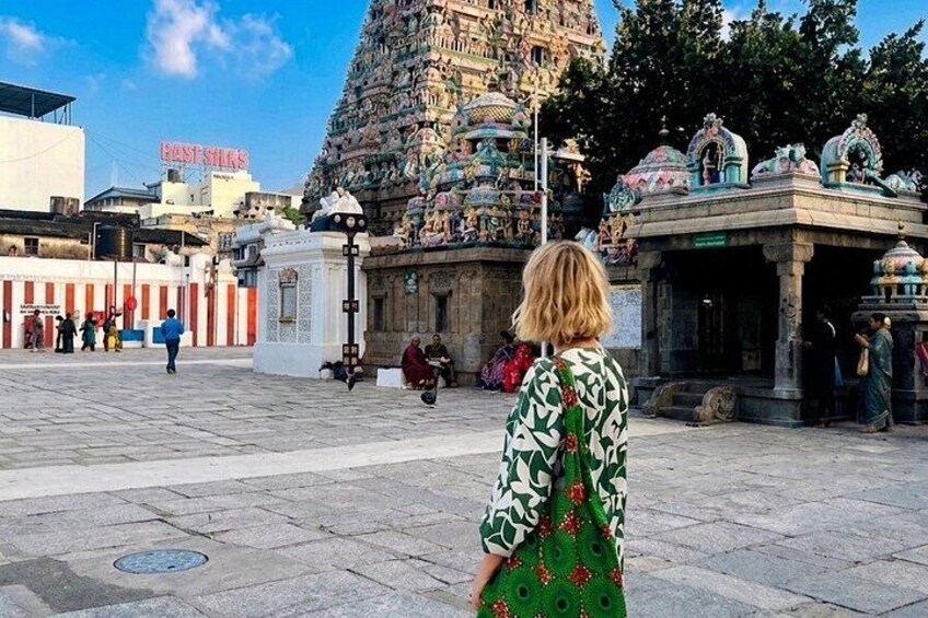 A temple with intricate carvings, a person in a green patterned dress, and a sign for 'East Silk.' 1
