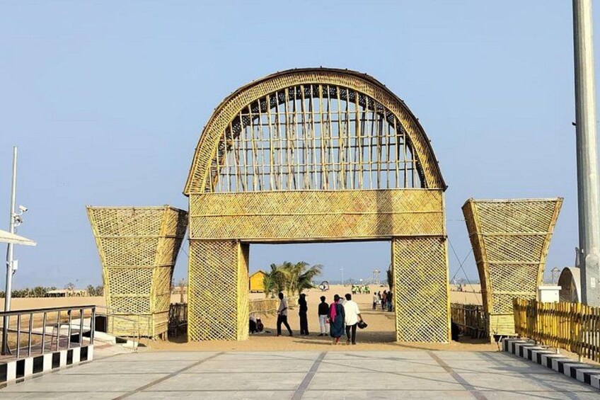 A large arched entrance with a lattice design, a paved walkway, and palm trees in the background. 4
