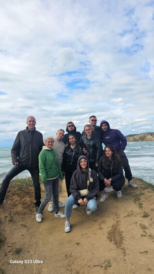 A group of people posing on a sandy beach with the ocean and a cloudy sky in the background. 3