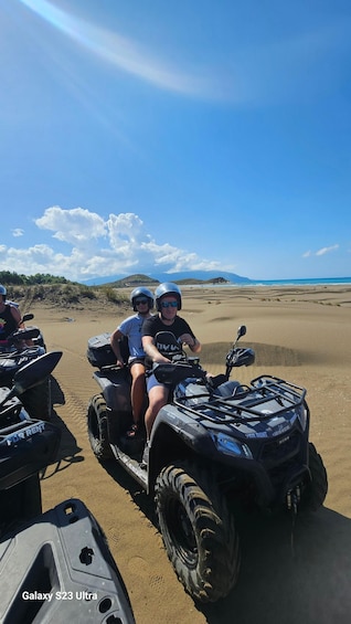 Two people on an ATV on a sandy beach with a clear sky. 5