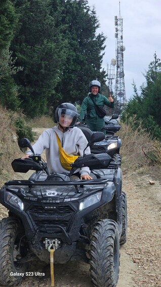 Two people on a Galaxy S23 Ultra ATV on a dirt path with trees and a communication tower in the background. 4