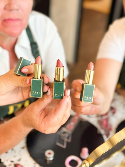 A person holding three lipsticks with the brand name 'PATI' on them. 5