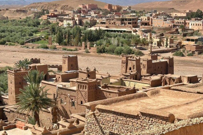 A desert town with traditional architecture, palm trees, and a mountainous backdrop. 2