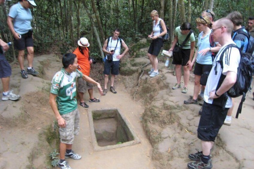 Un grupo de personas observando una excavación cuadrada en un área boscosa. 4
