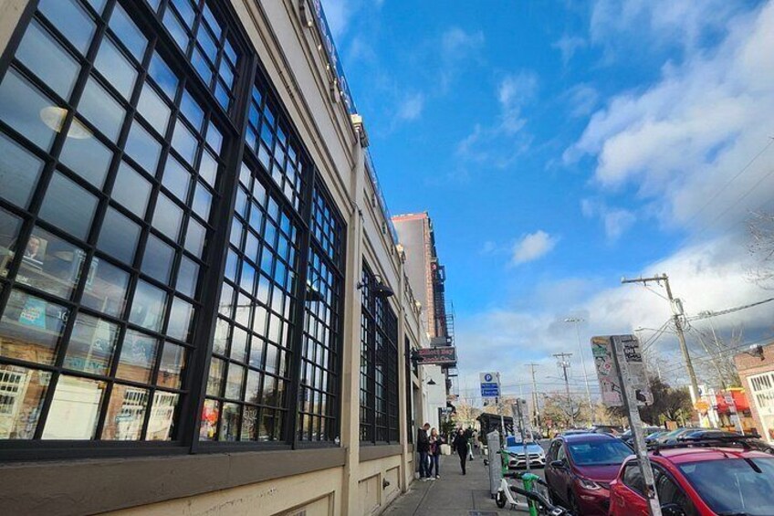 Una strada con auto parcheggiate, un edificio con ampie vetrate e un cielo sereno. 4