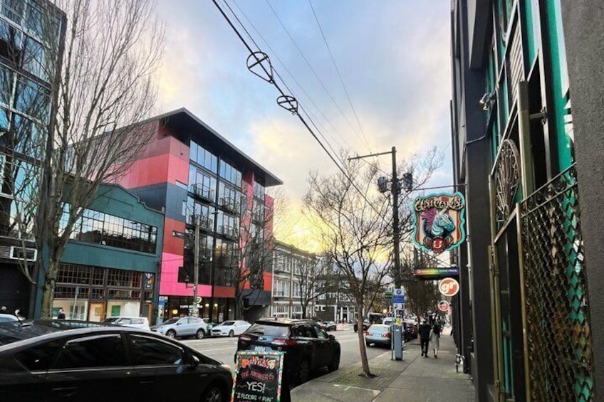 A street with a colorful building, parked cars, and a signboard. 4