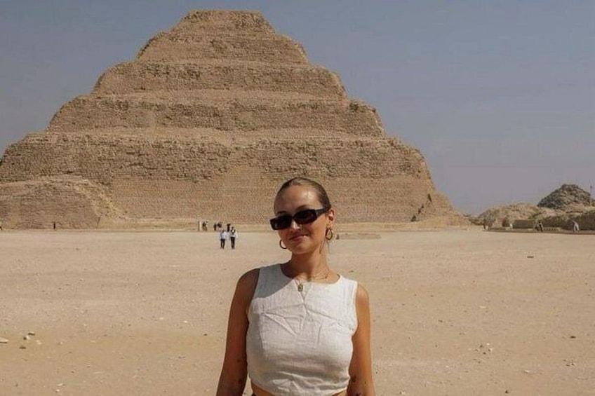 A person standing in front of a large pyramid in a desert landscape. 3