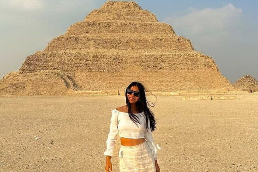 A person standing in front of a large pyramid structure in a desert landscape. 5