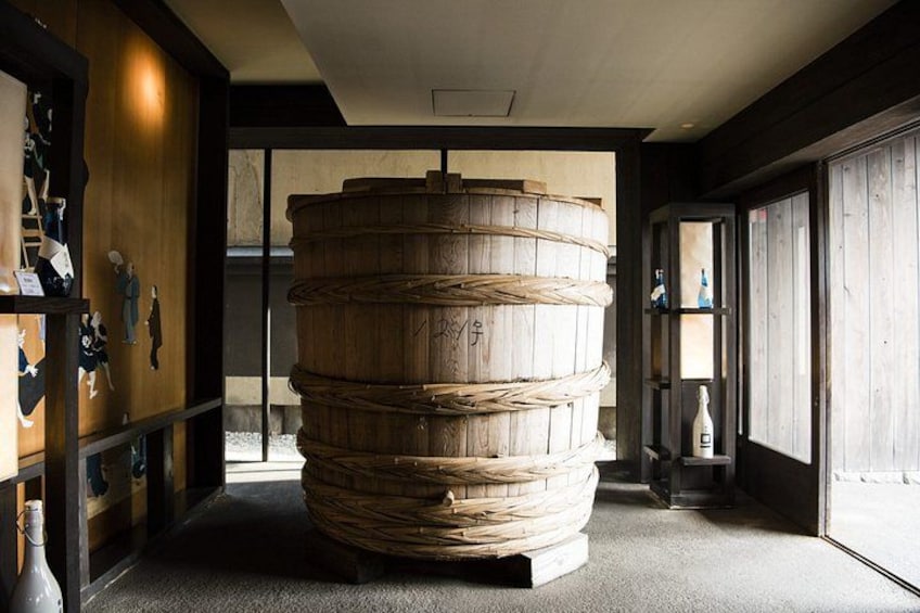 A large wooden barrel in a room with a tiled floor and wooden walls. 4