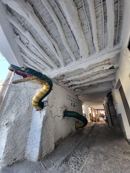 A corridor with a snake sculpture on the wall and a ceiling with exposed beams. 2